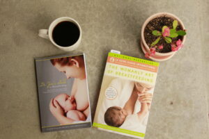 two books laying on concrete with a mug of coffee and a potted flower